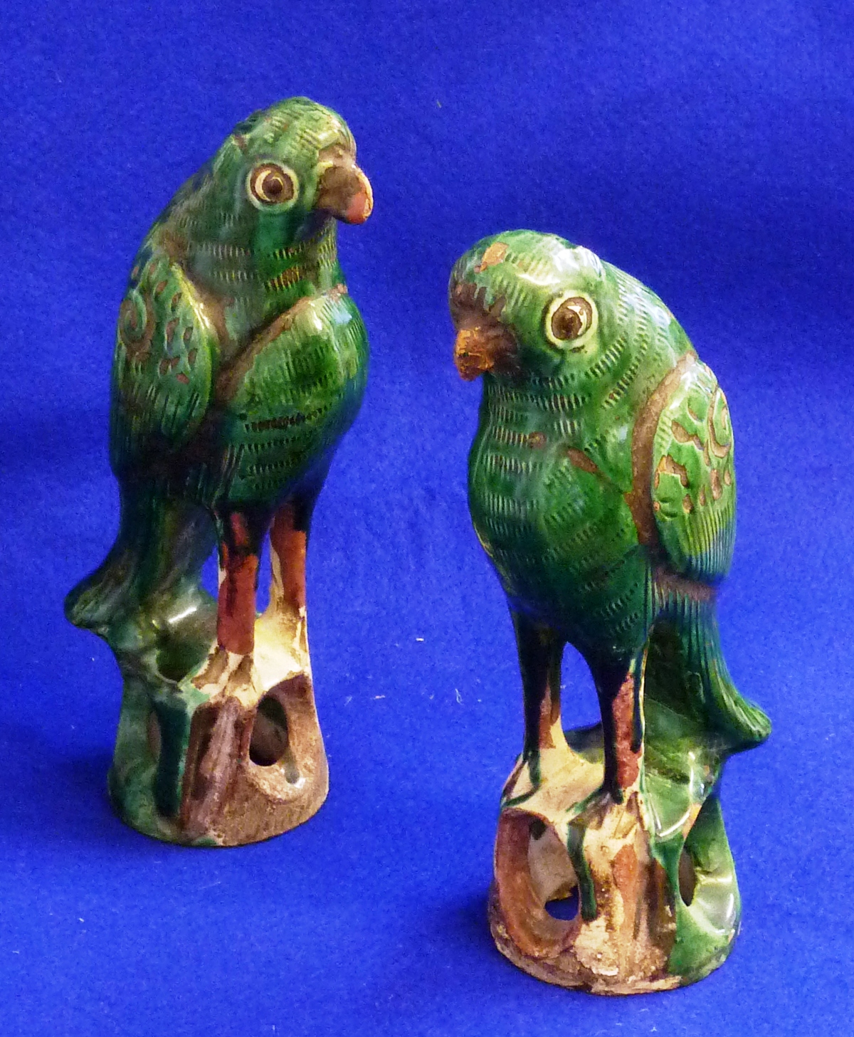 A pair of Chinese Famille vert enamelled biscuit Models of Parrots, each standing on pierced