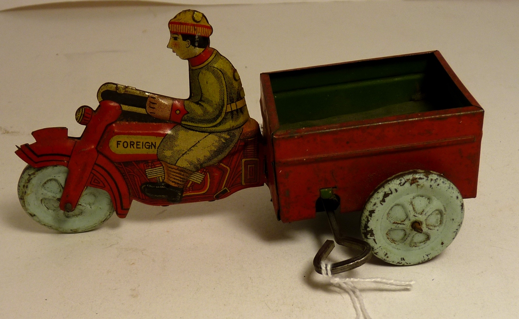 A Foreign made tinplate clockwork motortrike trailer with rider, colour printed detail and with