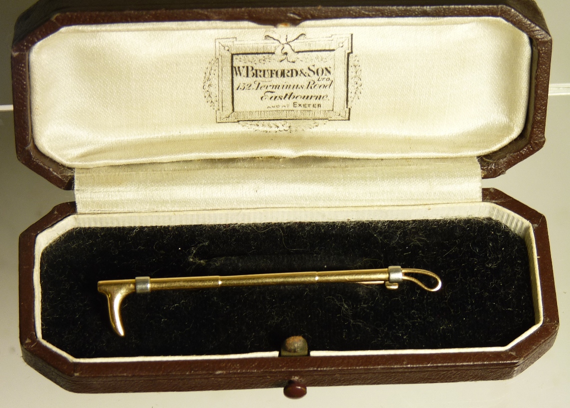 A gold stock pin in the form of a hunting crop in original case, 4.5g together with two decorative