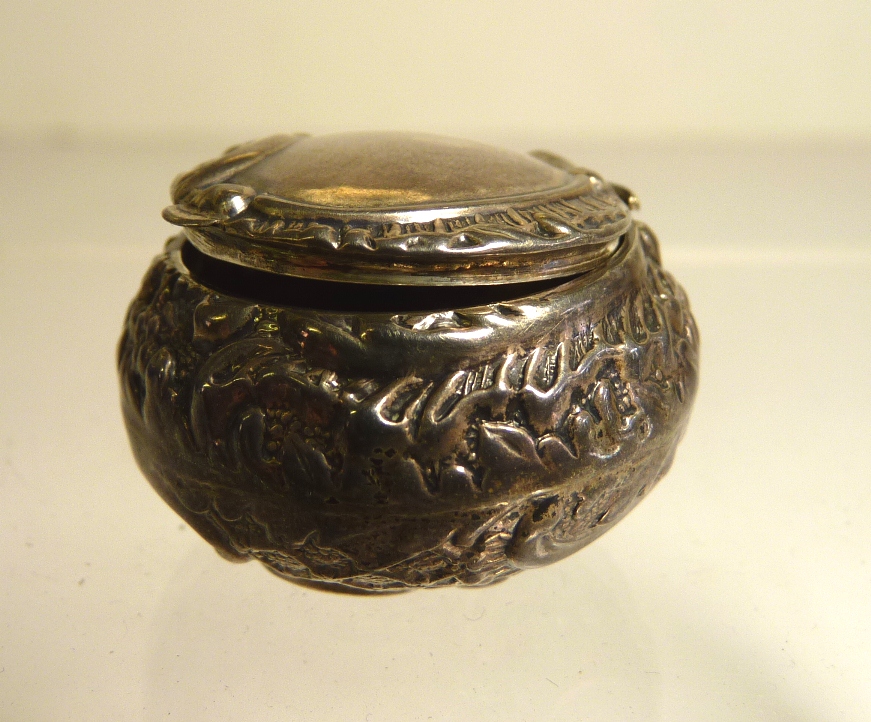 A small silver spherical pill box with chased scroll and foliate decoration, hinged lid with