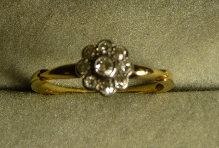 An Edwardian 18ct gold and diamond ring milgrain set in a flower head design