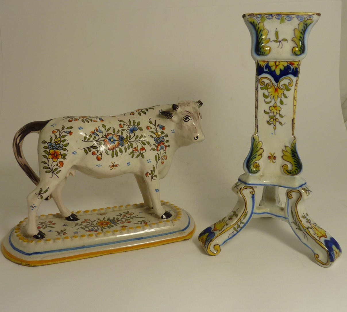 A Continental faience figure of a cow painted with floral sprigs and on rectangular base, 15cms high
