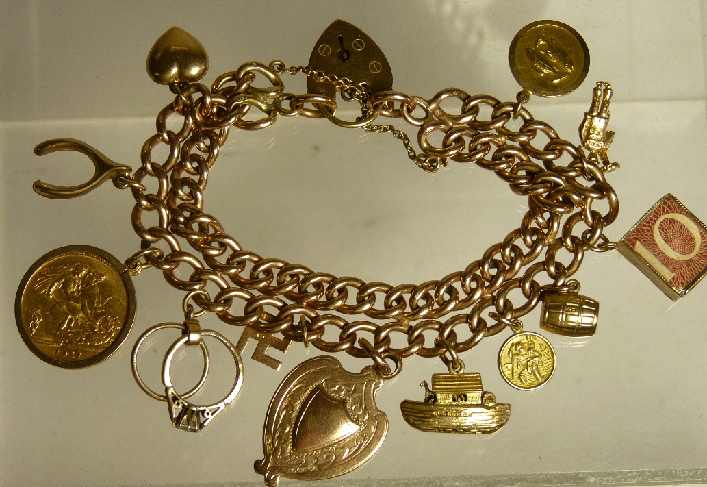 A 9ct gold double strand curb link charm bracelet with attached charms including a George V half