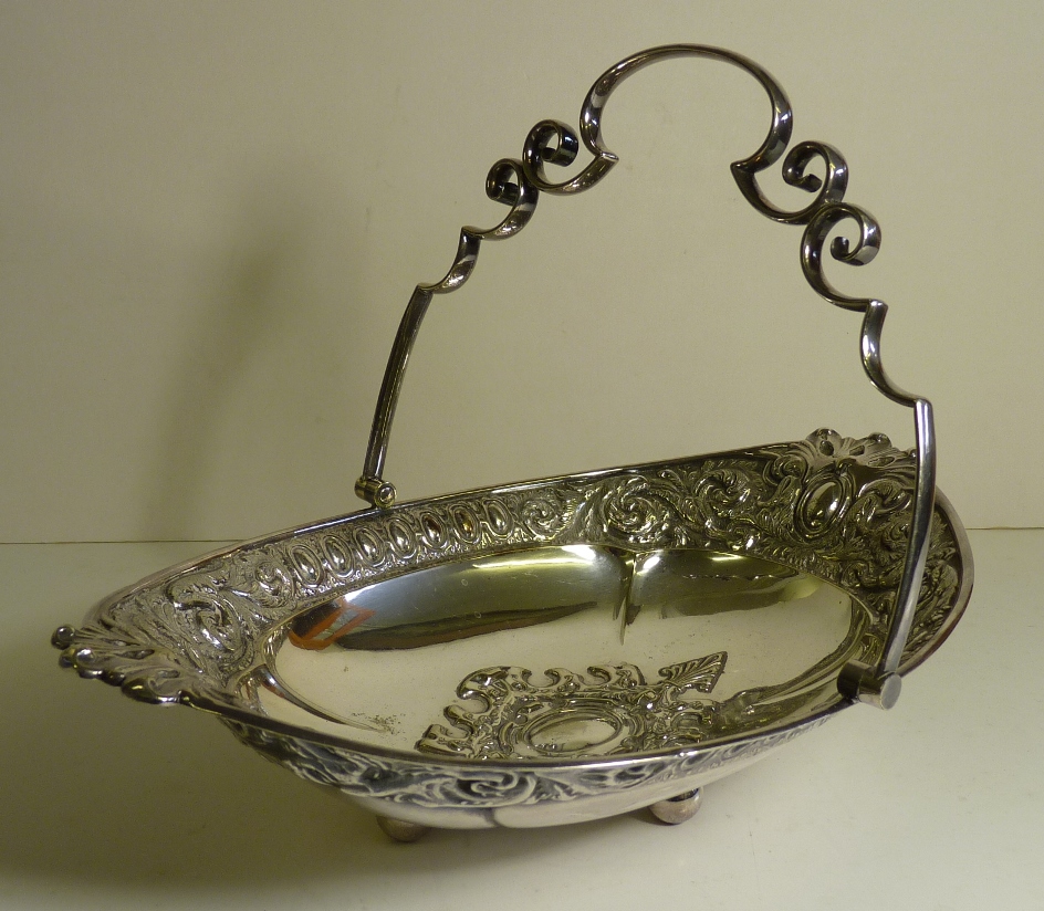 A late Victorian decorative silver plated cake or bread basket with multi scroll swing handle, crisp