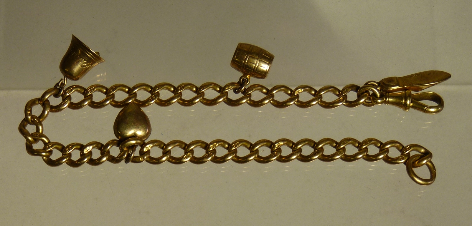 An 18ct gold curb link bracelet with four attached 9ct gold charms, 22.8g