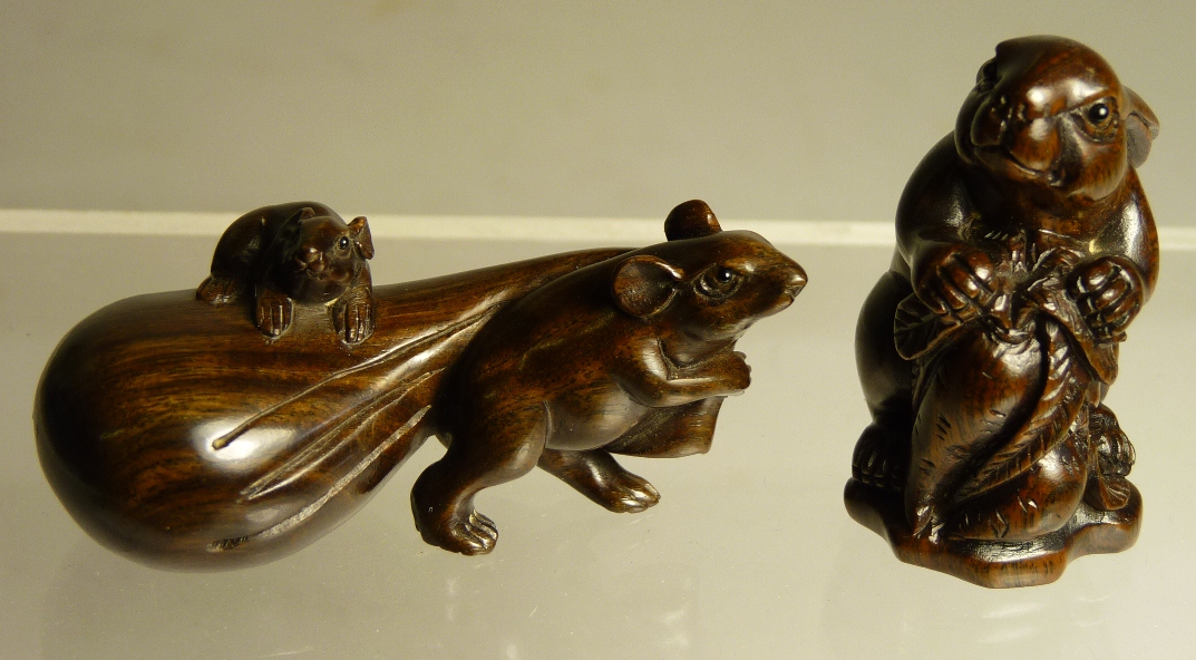 A Japanese carved wood netsuke of a rat pulling a sack with a young rat perched on top, scratched