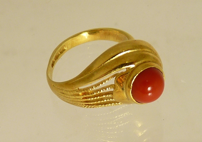 An 18ct gold adjustable size ring, set with a central circular cabochon red stone (possibly coral)