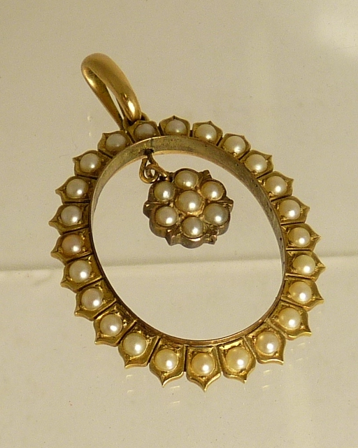 A gold metal oval, open pendant piece, the frame set with split pearls with central flowerhead