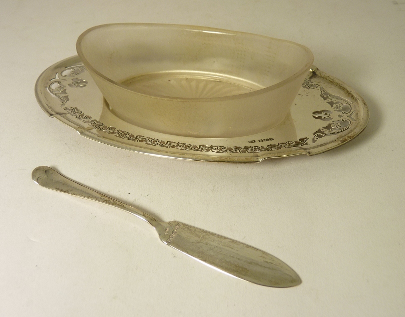 A glass butter dish on pierced oval silver stand Sheffield 1936 and a silver butter knife
