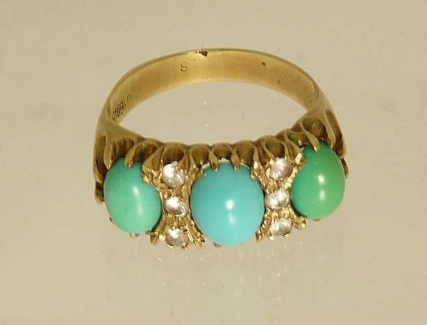 A 9ct gold dress ring set with three oval cabochon turquoise, spaced with colourless synthetic