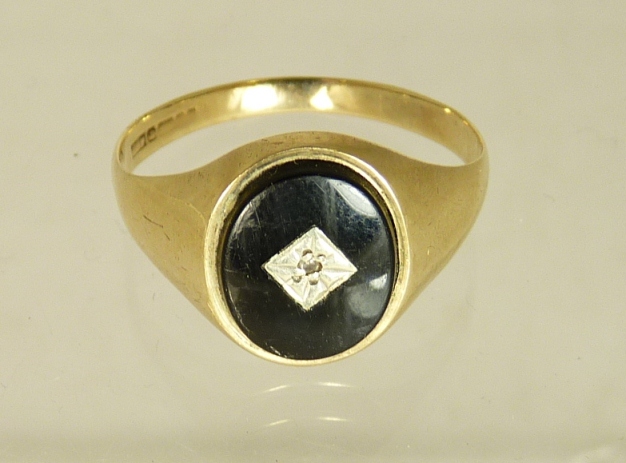 A gents 9ct gold signet ring, set with an oval black onyx panel. The panel inlaid with a gold