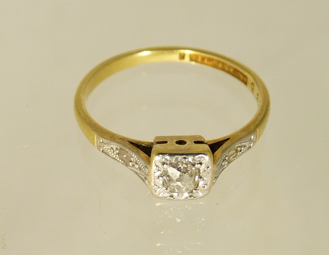 An 18ct gold and platinum mounted diamond ring, set with a tiny diamond to each shoulder, the