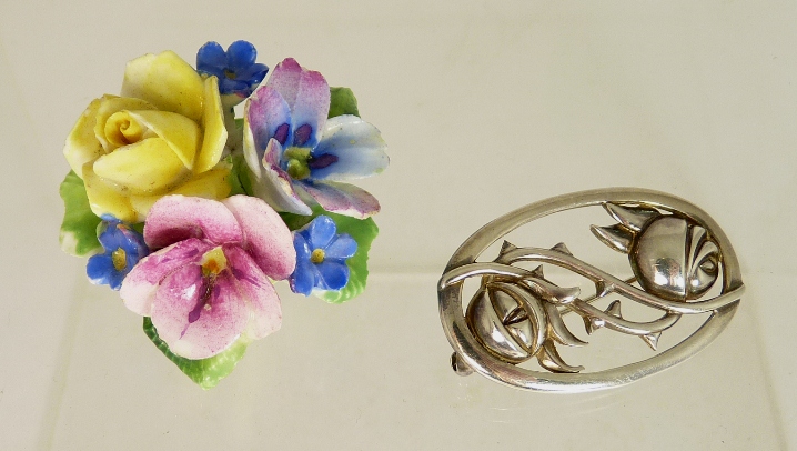 An oval silver brooch of open work design, with inset Scottish rose decoration in the style of