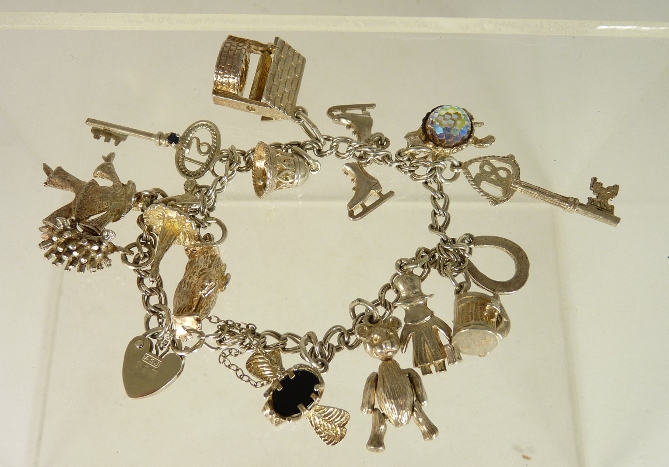 A small silver charm bracelet with attached silver charms including an articulated teddy bear, a