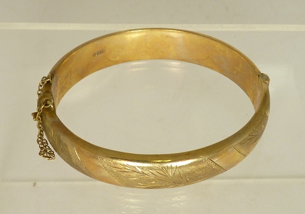 A 9ct gold hinged bangle with bright cut engraved floral decoration 17g approx.