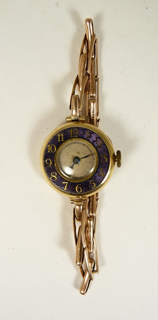 A 9ct gold cased ladies wristwatch on a 9ct gold expanding strap, the circular watch with mauve