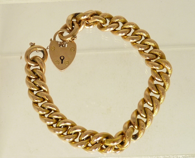 A 9ct gold padlock hollow link bracelet, each link half engraved with scroll and dot decoration.