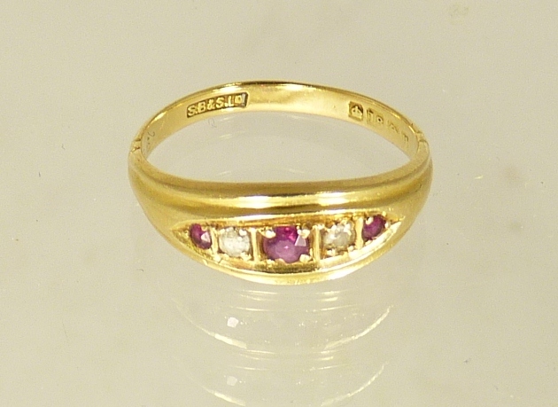 An 18ct gold ring set with three rubies and two small diamonds, size M+.