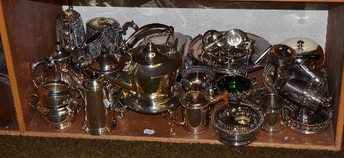 A shelf of silver plated items including tea services, trays, entree dishes and covers, cake