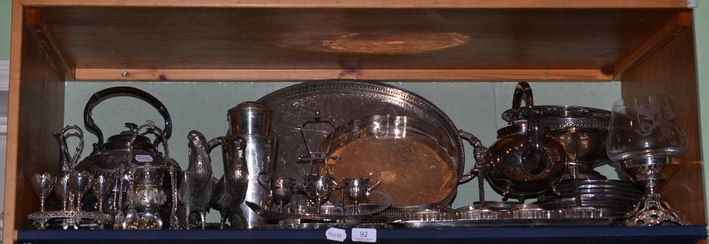 A shelf of silver plated ware including galleried trays, cake dishes, comports, tea kettle, place