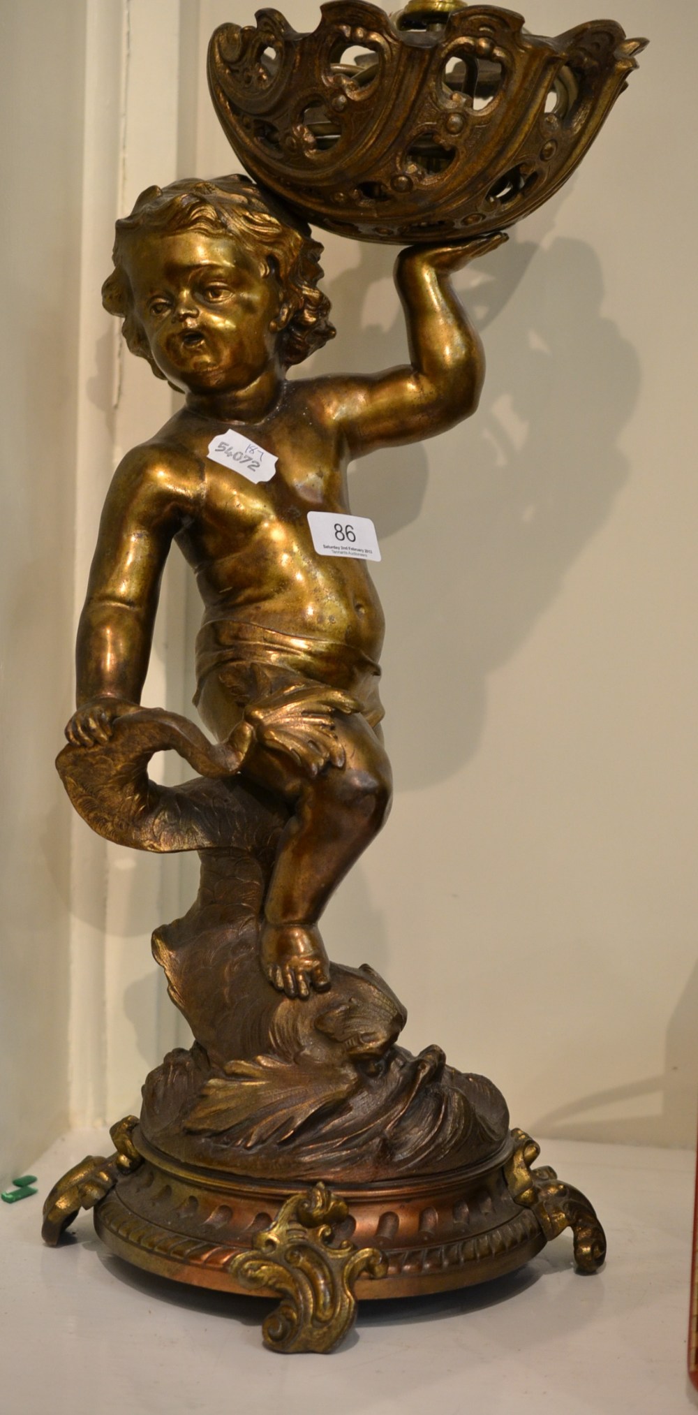 A large gilt metal table lamp modelled as a putto with dolphin