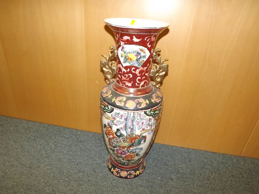 A tall Oriental vase, profusely decorated with images of exotic birds and flowers with gilded
