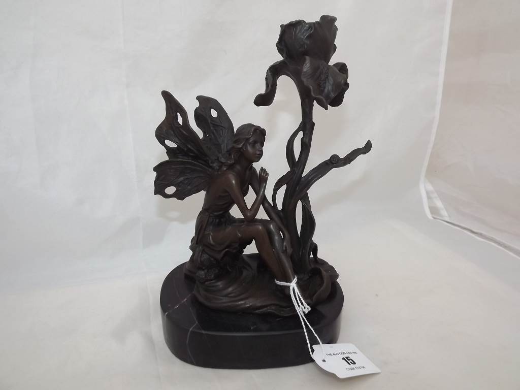 A good quality hot cast bronze depicting a fairy by a candlestick in the form of a flower mounted on