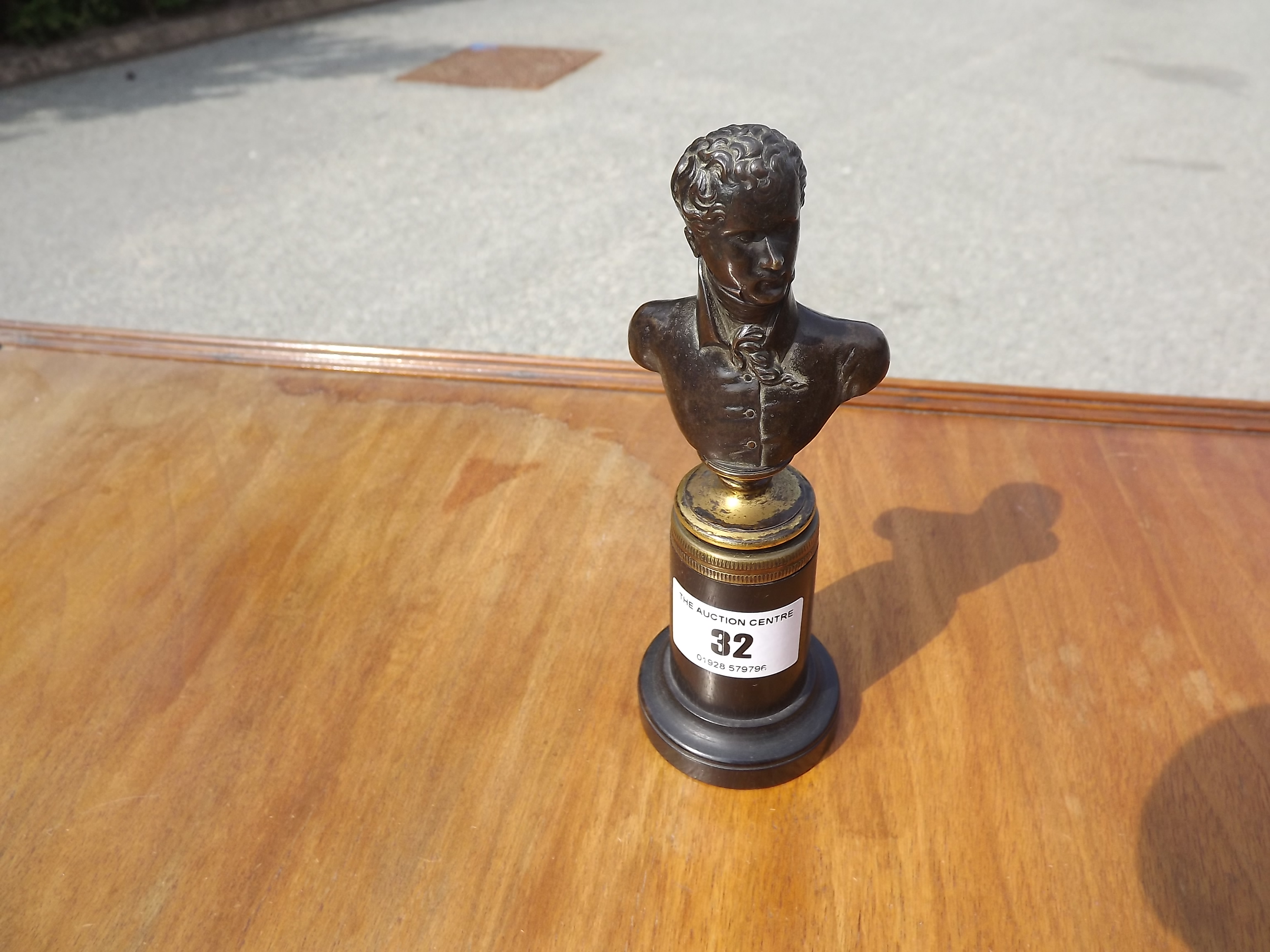 A miniature bronze bust depicting a gentleman mounted on an ebonised plinth 14.5cm (h)