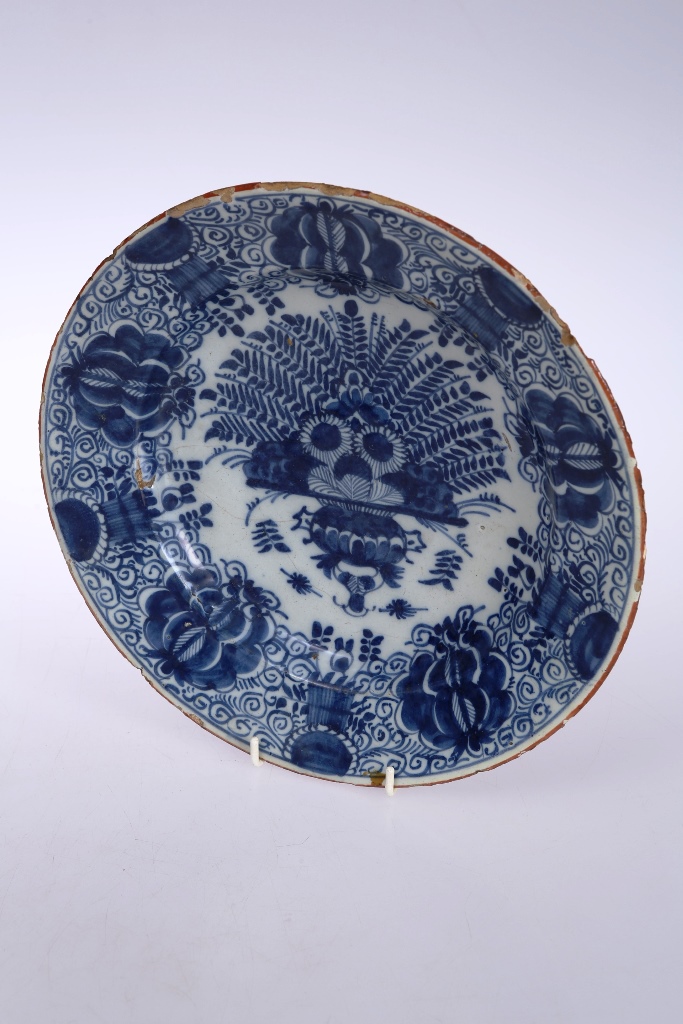 An 18th century Delft plate, circular, blue painted with a vase of flowers, painted mark verso.