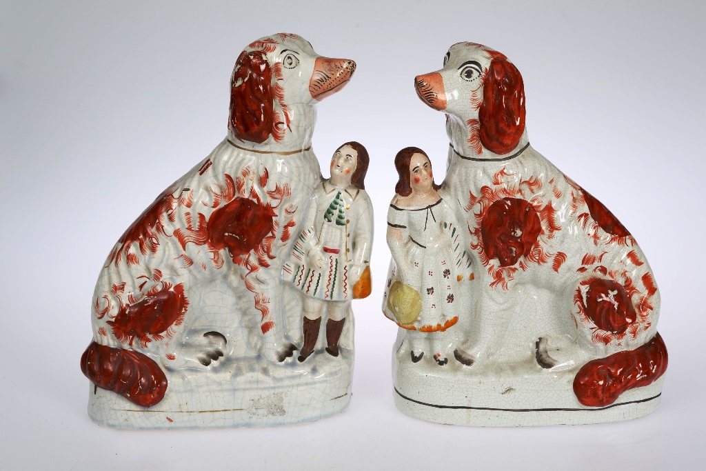 A pair of 19th century Staffordshire pottery groups, modelled as seated spaniels with a boy and girl