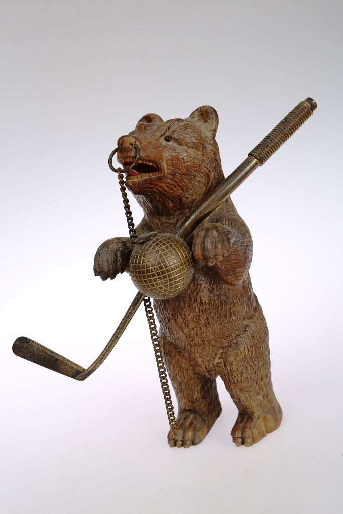 A Black Forest bear vesta holder, circa 1880, the carved bear standing holding a golf club and