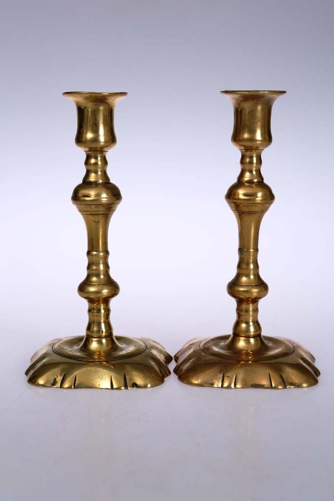 A pair of late 18th century brass candlesticks, with knopped baluster stem above a shaped square