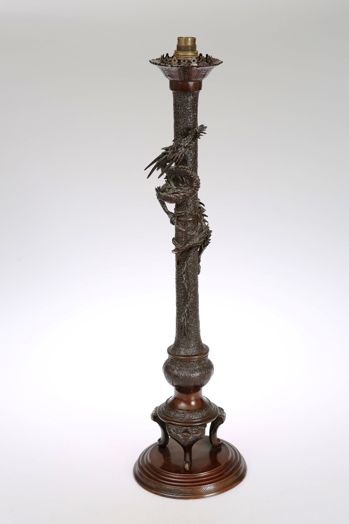 A Japanese bronze table lamp, the cylindrical stem being climbed by an entwined dragon, raised on