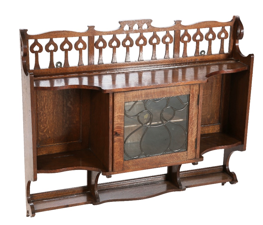 An Arts & Crafts oak hanging cabinet, the gallery carved and pierced with stylised Art Nouveau