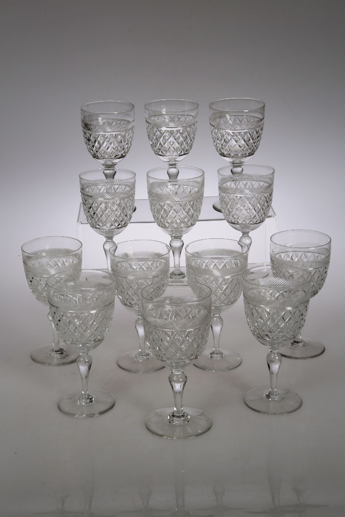 A group of thirteen similar Georgian style cut glass wines, each with diamond cut panels, some