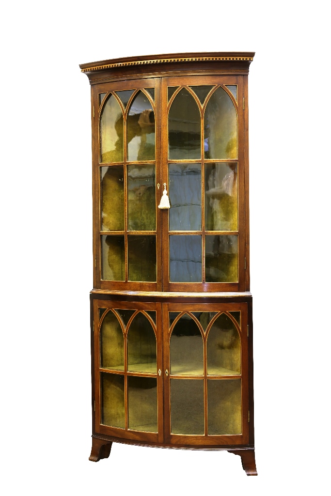 A 19th century mahogany floor standing double corner cupboard, bow-fronted, the dentil cornice above