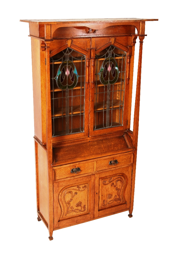 An Art Nouveau oak bureau bookcase, the over-hanging flat copy with shaped apron, supported by