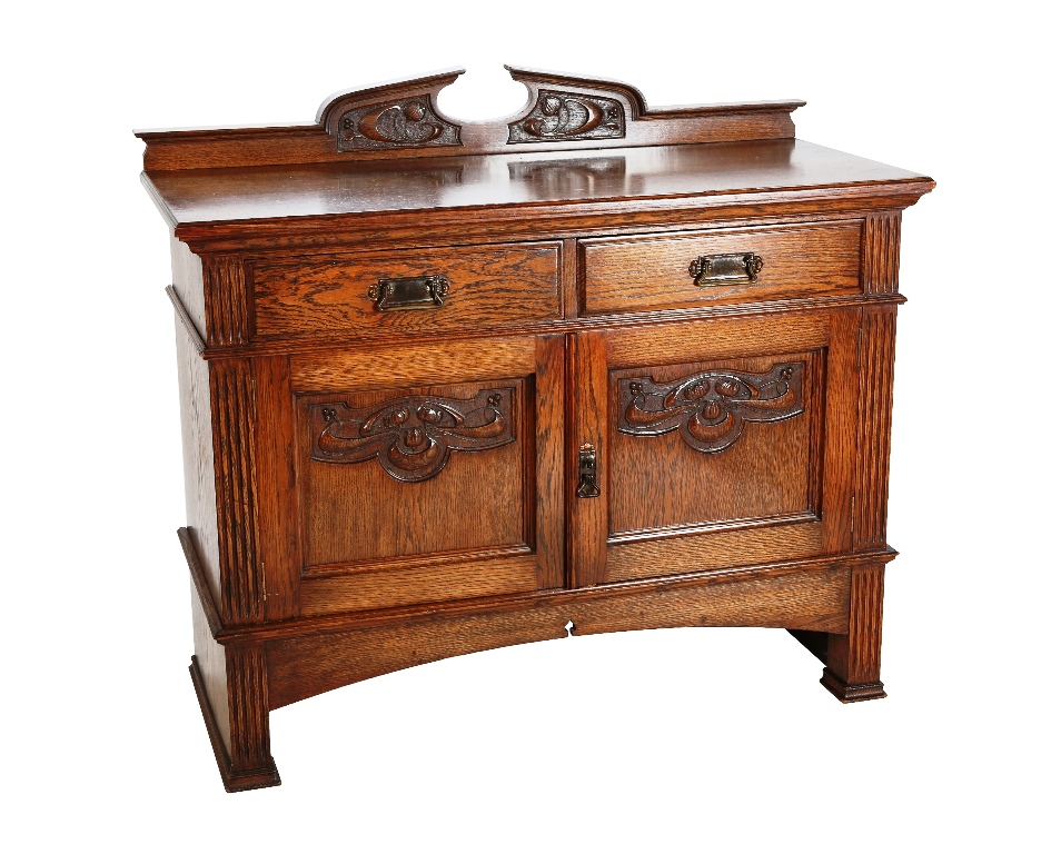 An Arts & Crafts oak sideboard, the rectangular moulded top, with foliate carved backboard, above