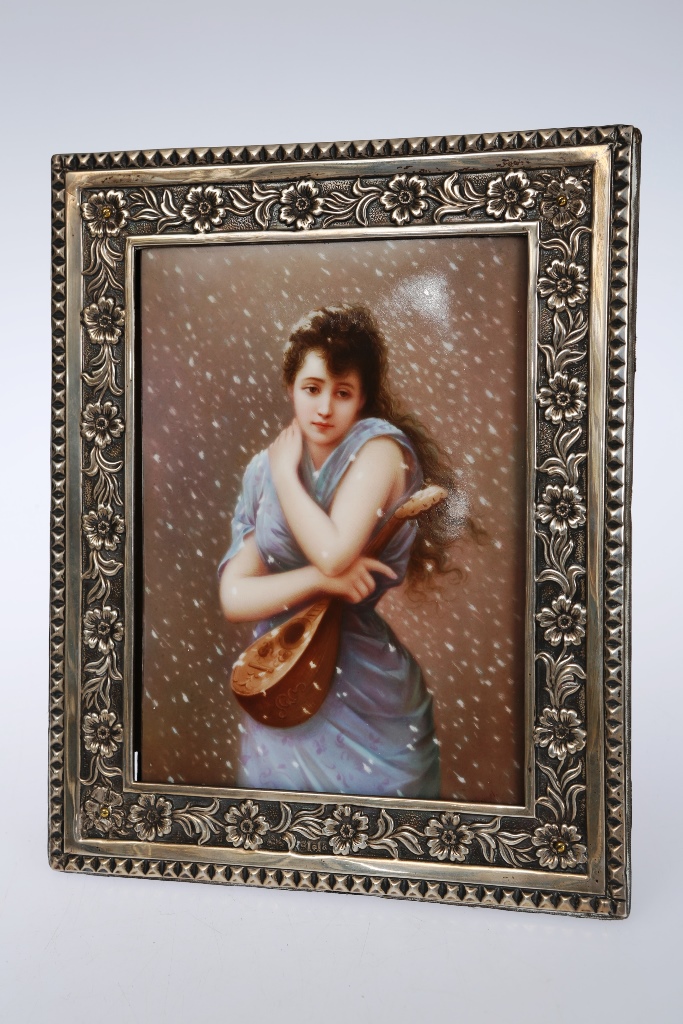 A KPM porcelain plaque, the rectangular panel painted with a girl holding a mandolin as the snow