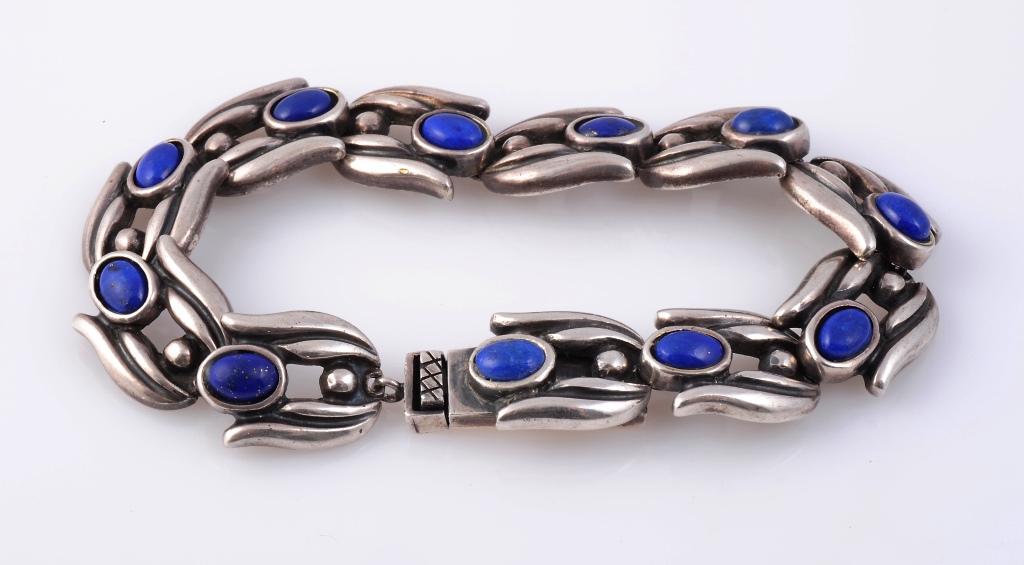 An Art Deco lapis lazuli and silver bracelet, the eleven moulded shaped links each set with a
