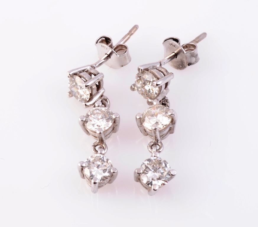 A pair of diamond drop ear studs, the three uniform size brilliant cut diamonds four claw set in