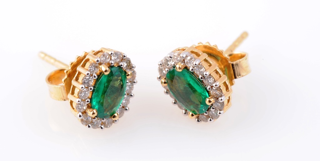 A pair of emerald and diamond ear studs, the oval mixed-cut emerald four claw set within a bezel of