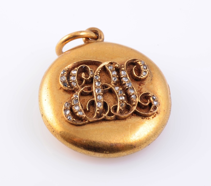 A diamond set locket, circa 1900 of simple circular design; the front, of entwined raised initials