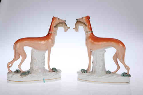 A pair of Staffordshire pottery models of greyhounds, 19th century, each modelled four square with a