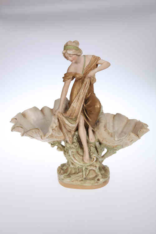 A Royal Dux porcelain centrepiece, modelled as a fisher girl sat upon a rock flanked by twin shell