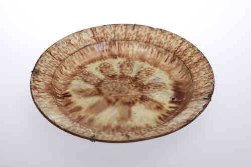 A 19th century pottery dish, probably Wearside, circular with mottled brown/yellow glaze,