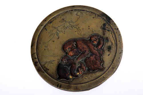 A Japanese bronze roundel, Meiji period, the circular disc decorated in low relief with playful