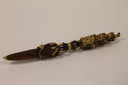 A bronze Tibetan phurba, with gilded multi-head terminal above mythical serpent shaped tip, length