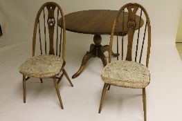 An Ercol elm extending pedestal table with leaf, width 150 cm, together with four matching