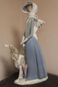 A Lladro figure - A Lady walking a dog in a strong breeze, height 40 cm. CONDITION REPORT: Small